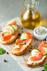 Salmon, cucumber and cream cheese bruschetta. Italian tapas, antipasti with vegetables, herbs and oil on grilled ciabatta and baguette bread. Sandwich.