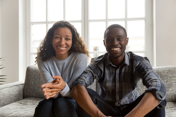 Happy friendly african couple looking at camera at home, smiling black husband and wife making...