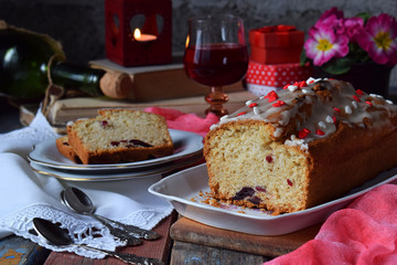 Dried fruit cake with raisins, apricots, cherry and glass of red wine, bottle and flower rustic wooden background. Valentines day still life. Sliced freshly baked fruitcake. Copy space for text