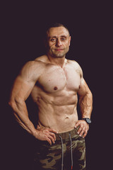 Portrait of a strong man involved in sports. Studio photo on a black background. The big pumped...