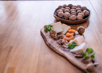 Nuts in focus with blur some peaces of the french cheese Petit Bonet and parsley on the wooden  desk hand made from olive tree near decorative mouse