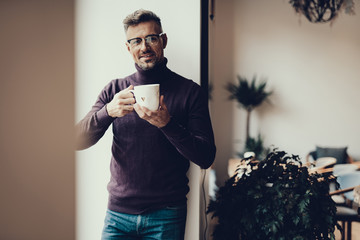 Friendly man with cup looking at camera and smiling