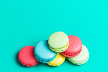 Cake blue, pink, yellow, green macaron or macaroon on turquoise background, top view