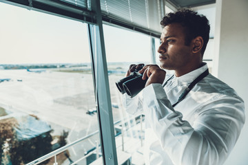 Dispatcher holding binocular in hands on work place