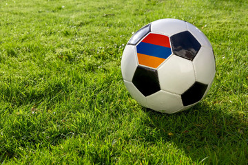 Fototapeta premium Football on a grass pitch with Armenia Flag