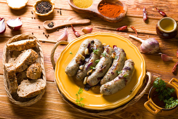 Raw white sausage on a wooden background with spices.