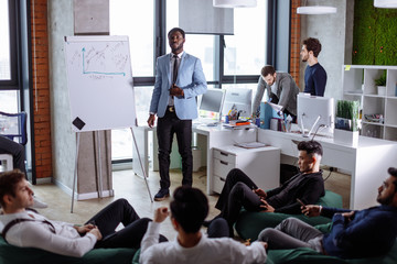 African American businessman presenting to his multiethnic colleagues his progressive ideas at a...