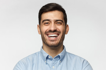 Portrait of handsome laughing business man, isolated on gray background