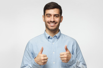 Portrait of excited business man making thumbs up gesture, isolated on gray background