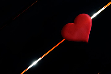 The heart lies on a black background and glowing diagonal lines. The fate of man, life and death