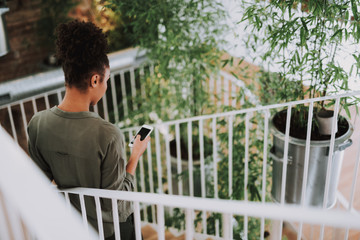 Afro american girl using cellphone while standing on stairs