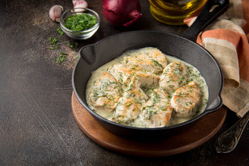 Chicken fillet or Turkey breast in creamy sauce with dill and garlic, in cast iron black pan on...