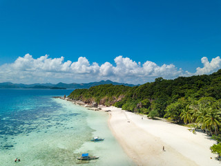 Aerial view of tropical beach on the island Malcapuya. Beautiful tropical island with sand beach, palm trees. Tropical landscape with shore and boat. Palawan, Philippines