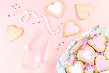 Happy Valentine's day greeting card with heart cookies, wine glasses and wine on pastel pink background.