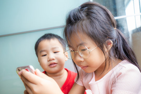 Sister and brother child playing smartphone in room