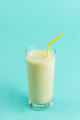 white smoothie from bananas. a portion of yogurt. close up photo. isolated blue background. drink for happy mood