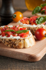 Italian tomato and cheese bruschetta. Tapas, antipasti with chopped vegetables, herbs and oil on grilled ciabatta and baguette bread.