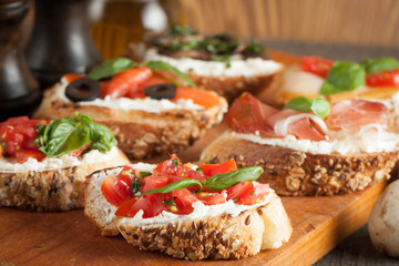 Italian tomato and cheese bruschetta. Tapas, antipasti with chopped vegetables, herbs and oil on grilled ciabatta and baguette bread.