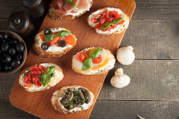 Italian tomato and cheese bruschetta. Tapas, antipasti with chopped vegetables, herbs and oil on grilled ciabatta and baguette bread.