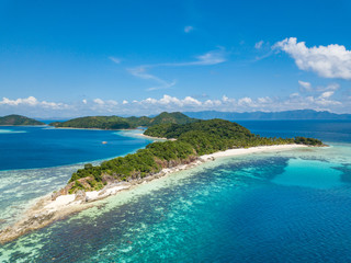 Fototapeta na wymiar Aerial view of tropical beach on the island Malcapuya. Beautiful tropical island with sand beach, palm trees. Tropical landscape with shore and boat. Palawan, Philippines