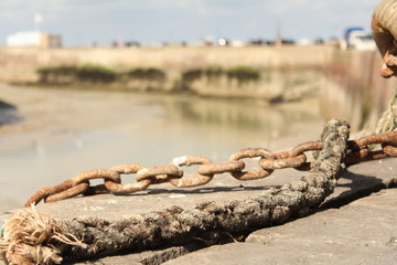 a rusty chain and a rope at the quay next to the harbour macro
