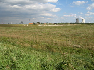 the green polder landscape in zeeland, holland with a nuclear power plant in the background in summer