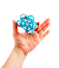 Female hand holding сhristmas cookie in a shape of blue snowflake with bite, isolated on white. New year holiday decoration, winter time food.