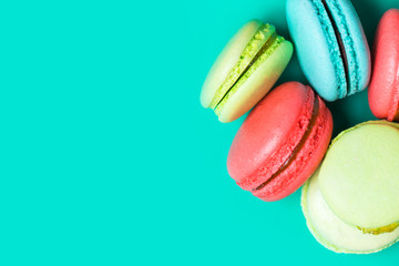Sweet and colorful french macaroons on turquoise background