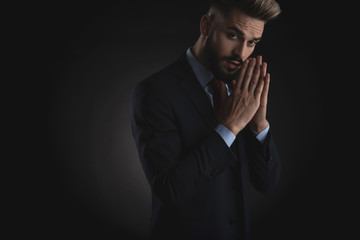 portrait of young businessman in navy suit praying