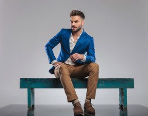 curious smart casual man sitting on bench looks to side