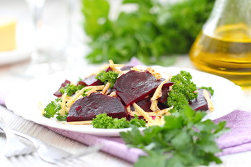 Salad with beet, cheese and greens served witn oil and balsamic vinegar