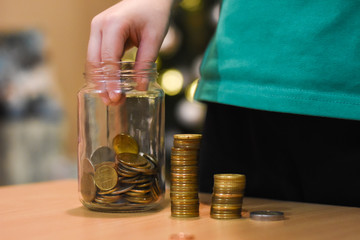 Boy putting coins in a glass jar. Concept of saving. Child save money for Christmas presents