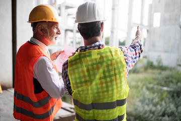 Team of architects and engineer in group on construciton site check documents and business workflow