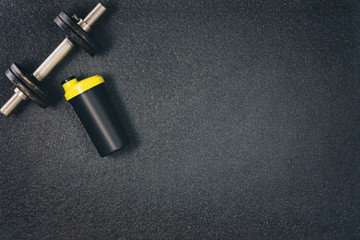 Fitness or bodybuilding concept background. Product photograph of old iron dumbbells on black grey, conrete floor in the gym. Photograph taken from above, top view with lots of copy space