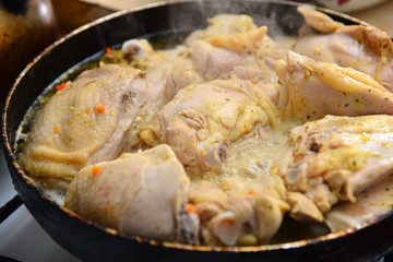 Fried chicken in a pan in oil with spices.