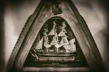 Tall ship model in triangular wooden frame, anchor,rope, isolated on blurred background, faded in...