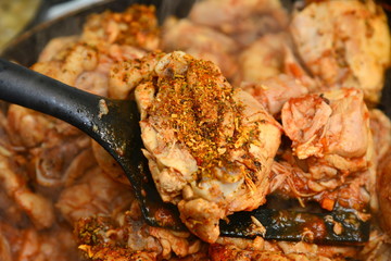 The cook mixes fried chicken with spices in a pan