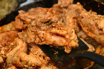 The cook mixes fried chicken with spices in a pan