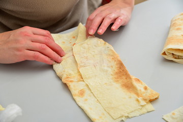 Cook wraps pita bread with meat, ketchup and mayonnaise.