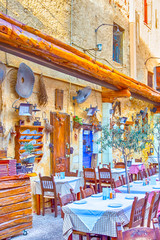 Classic Cretan open Air Restaurant in Chania with Served Tables and Artistically Decorated Walls.