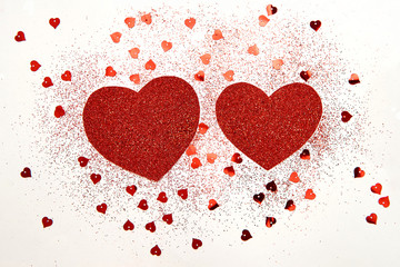 Two red hearts with sequins and small hearts on white background