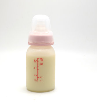 Baby bottle with milk and a measuring scale on the background of a lot of full bottles of breast milk. Mother's milk - the most healthy food for newborn