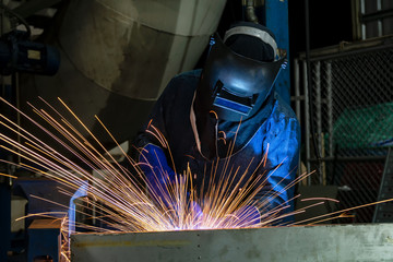 Industrial worker is welding repair steel part in factory