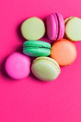 Flat lay of many colorful macaroons on on pink background.