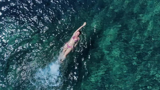 Aerial panorama on woman backstroke swimming in blue sea