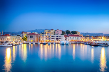 Fototapeta na wymiar Travel Concepts. Picturesque Image of Old Venetian Harbour of Chania with Fisihing Boats and Yachts on the Foregound Taken At Blue Hour in Crete, Greece