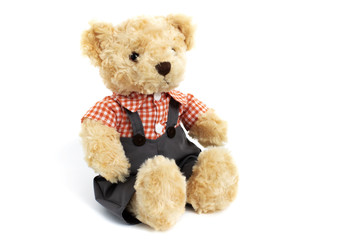 Dressed toy teddy bear in shirt and trousers is sitting on white background