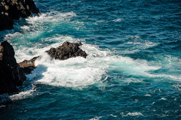 Stormy sea with white waves around the rock