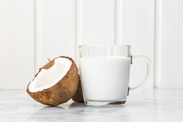Closeup of coconut milk in a glass and coconut halves