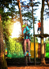 Obraz na płótnie Canvas the girl goes down the zip lines in the rope park